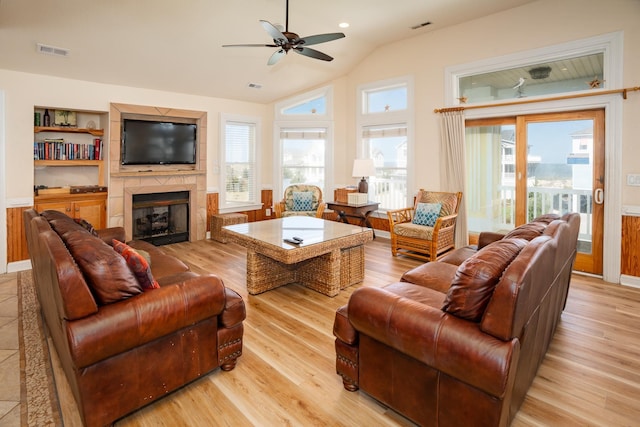 living area featuring light wood-type flooring, a fireplace, visible vents, and a healthy amount of sunlight