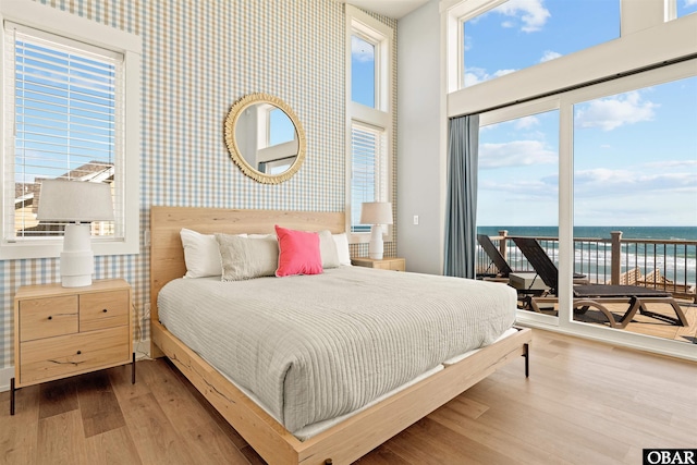 981 Lighthouse Dr Lot 10, Corolla, NC 27927 - bedroom featuring wallpapered walls, access to exterior, multiple windows, a water view, and wood finished floors