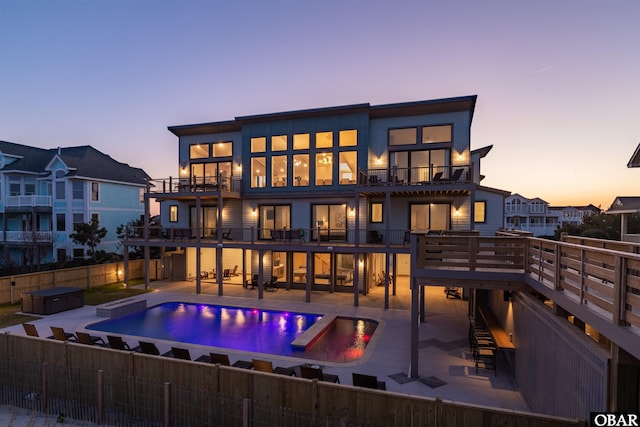 981 Lighthouse Dr Lot 10, Corolla, NC 27927 - back of property at dusk featuring a balcony, an in-ground hot tub, a fenced backyard, and a patio