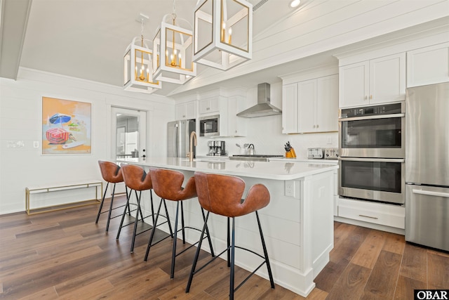 981 Lighthouse Dr Lot 10, Corolla, NC 27927 - kitchen featuring appliances with stainless steel finishes, wall chimney range hood, an island with sink, a kitchen breakfast bar, and light countertops