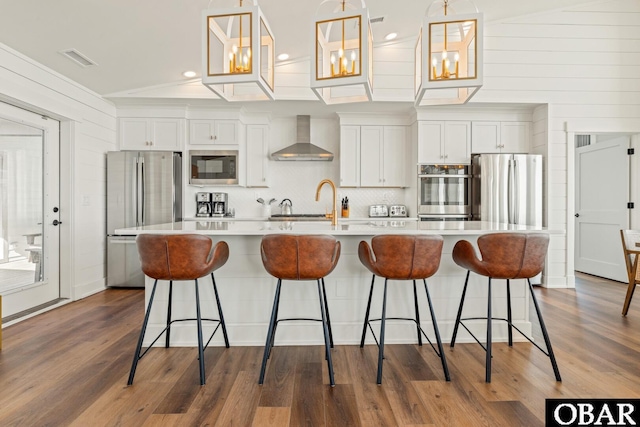981 Lighthouse Dr Lot 10, Corolla, NC 27927 - kitchen featuring appliances with stainless steel finishes, wall chimney range hood, a spacious island, dark wood-type flooring, and light countertops