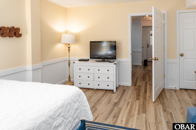 bedroom with wainscoting and light wood finished floors