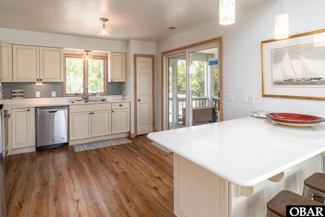 kitchen featuring a kitchen breakfast bar, dishwasher, a sink, light countertops, and a peninsula