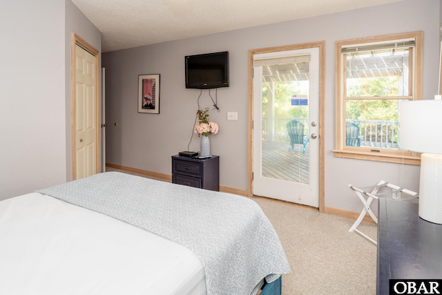 carpeted bedroom featuring baseboards and access to exterior