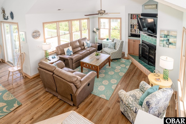 living area featuring plenty of natural light, a ceiling fan, light wood finished floors, and a fireplace