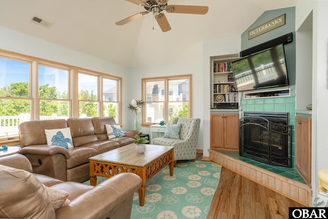 living room with a fireplace, lofted ceiling, wood finished floors, and visible vents