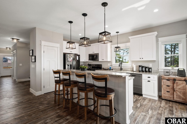 kitchen featuring white cabinets, dark wood-style floors, a kitchen island, a breakfast bar, and stainless steel appliances