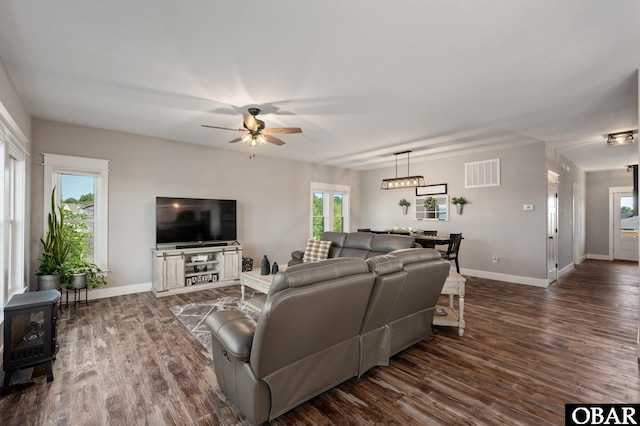 living room with a ceiling fan, visible vents, dark wood finished floors, and baseboards