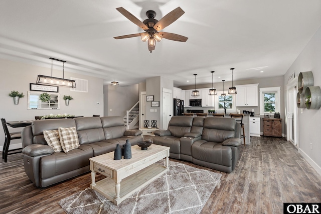 living area with dark wood-type flooring, visible vents, stairway, and baseboards