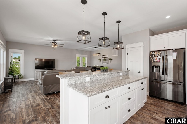 kitchen with dark wood-type flooring, a kitchen island, light stone countertops, and stainless steel fridge with ice dispenser