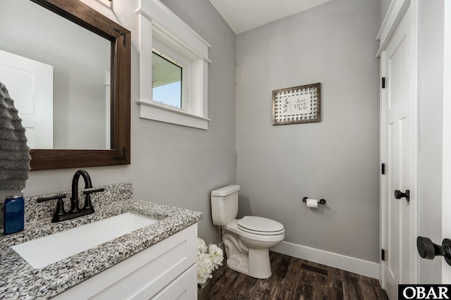 half bathroom featuring toilet, wood finished floors, visible vents, vanity, and baseboards