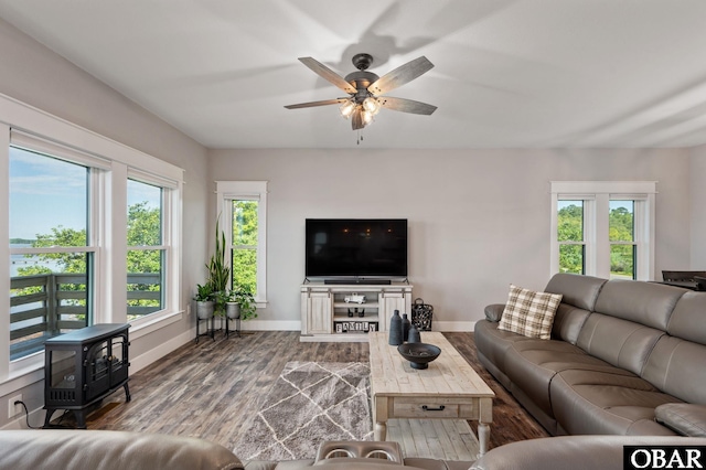 living room featuring a wood stove, baseboards, and wood finished floors