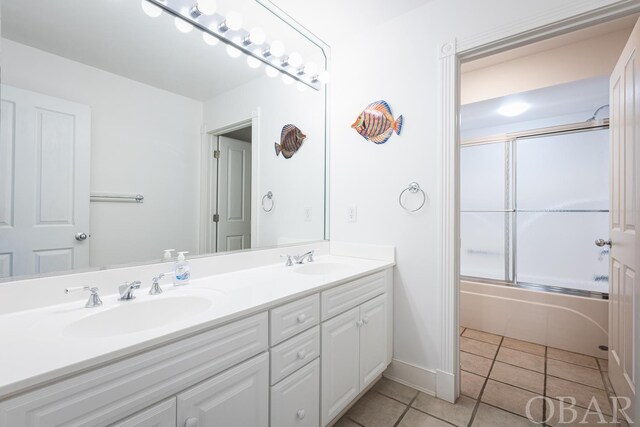 full bath with double vanity, combined bath / shower with glass door, a sink, and tile patterned floors