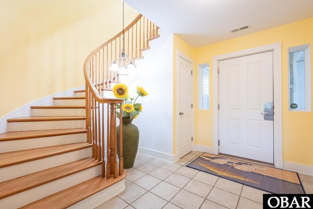 foyer entrance featuring light tile patterned floors, baseboards, stairway, and visible vents