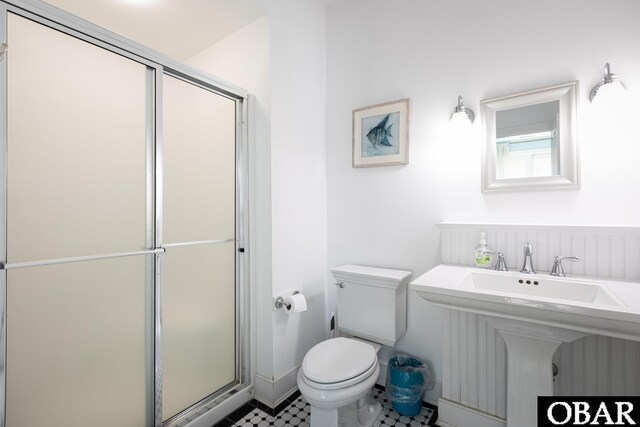 bathroom featuring toilet, a shower stall, and a sink