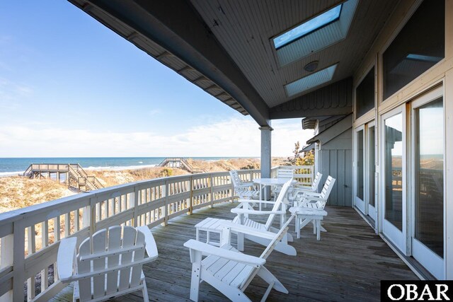 wooden terrace with a water view and a view of the beach