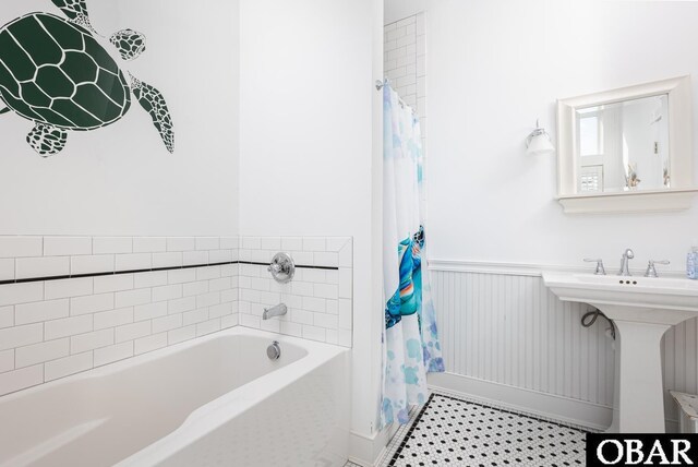 bathroom featuring tile patterned flooring, shower / bath combo, a sink, and wainscoting