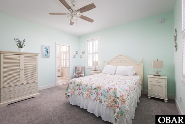 carpeted bedroom featuring a ceiling fan, ensuite bath, and baseboards