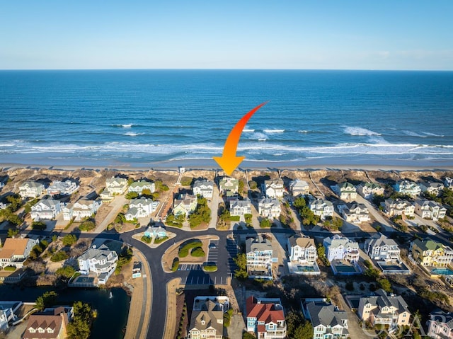 drone / aerial view featuring a water view, a residential view, and a beach view