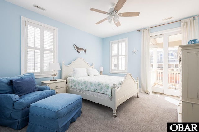 carpeted bedroom with access to outside, visible vents, and ceiling fan