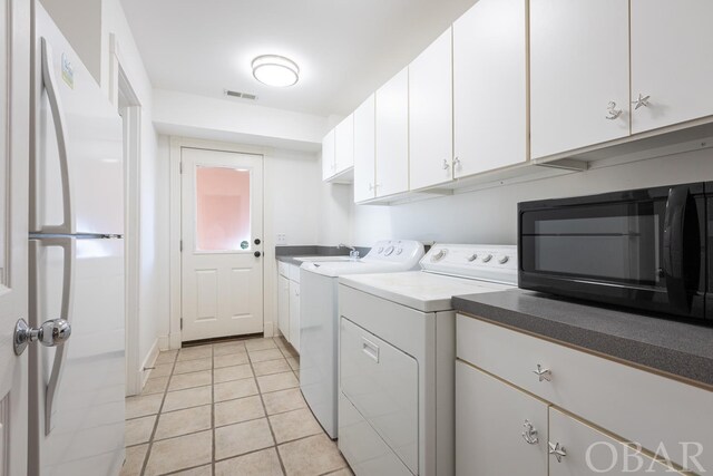 laundry area with light tile patterned flooring, independent washer and dryer, cabinet space, and visible vents