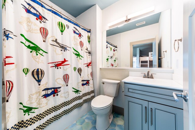 bathroom with shower / tub combo with curtain, vanity, toilet, and tile patterned floors