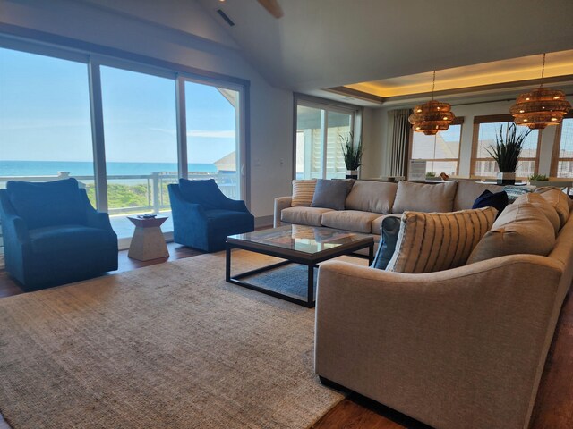 living area with a water view, visible vents, a raised ceiling, and wood finished floors