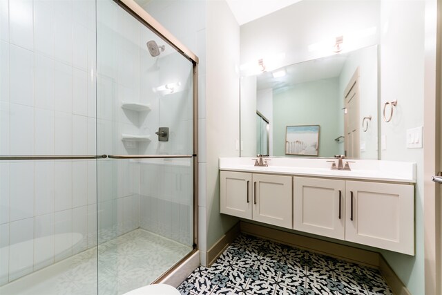 bathroom featuring a sink, double vanity, a shower stall, and baseboards