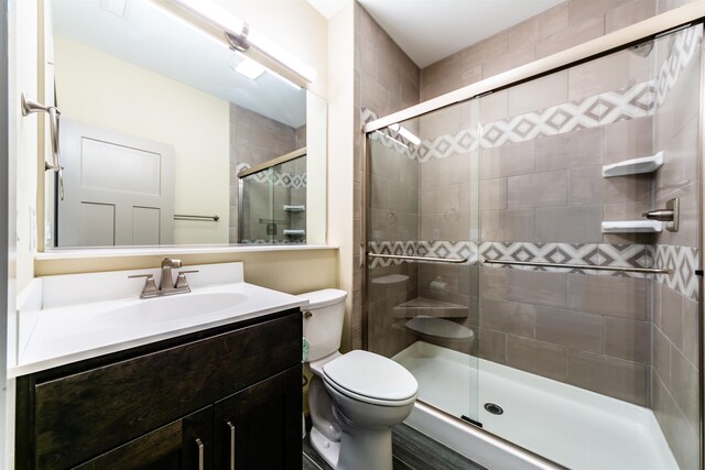 full bathroom featuring a shower stall, toilet, and vanity