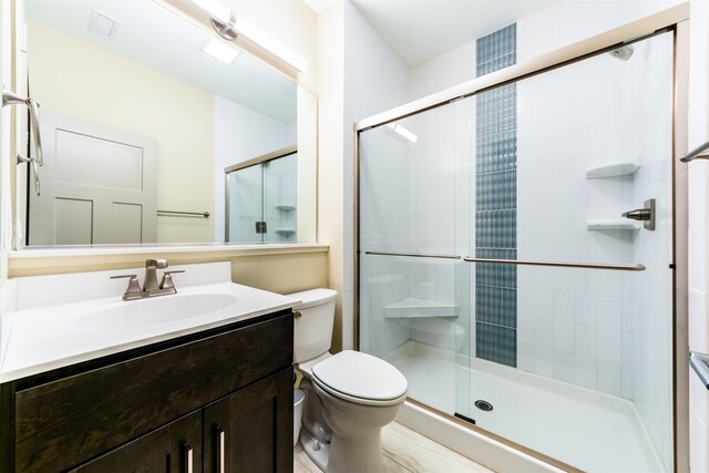 full bathroom with a stall shower, vanity, and toilet