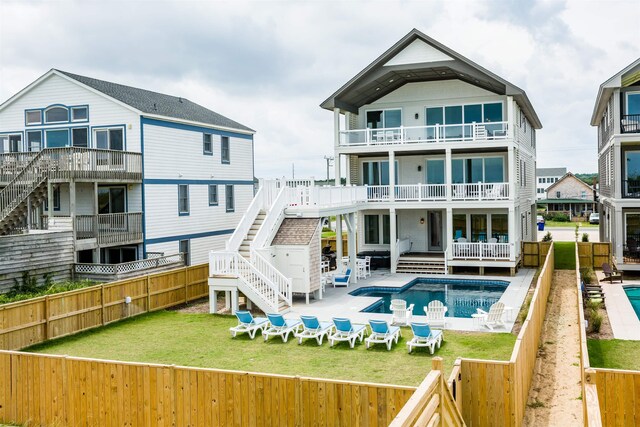 rear view of house with a fenced in pool, a patio area, a balcony, a fenced backyard, and stairs