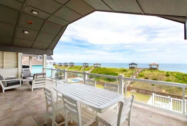 balcony with a patio, outdoor dining area, and a water view