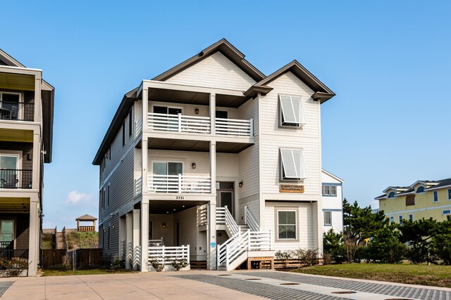 view of front of house with driveway, fence, and a balcony