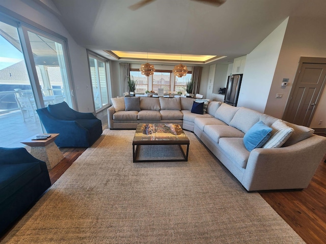 living room with a healthy amount of sunlight, dark wood-style floors, and a raised ceiling