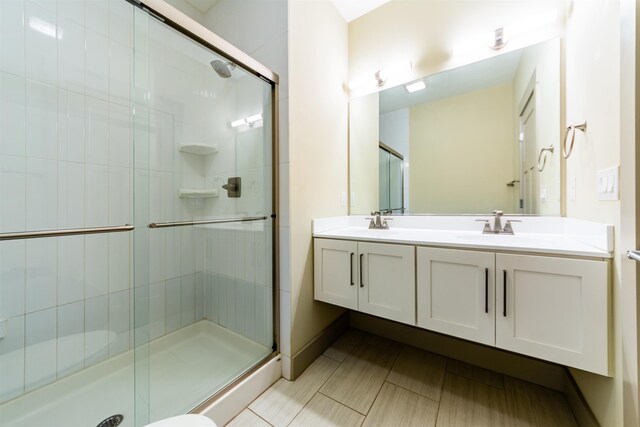 bathroom with double vanity, a stall shower, and a sink