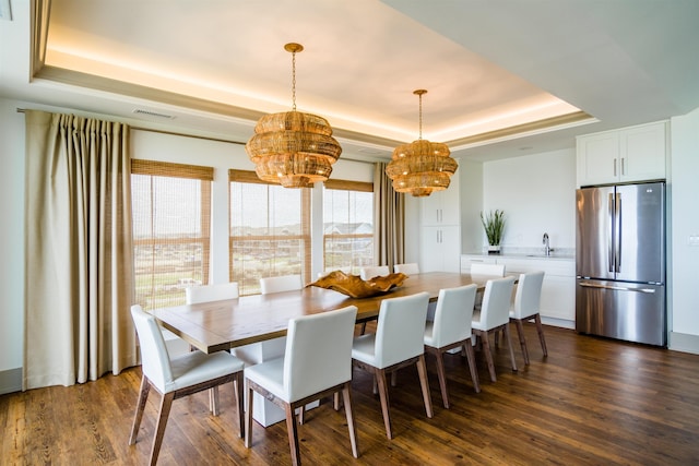 dining area with a tray ceiling, visible vents, and dark wood finished floors