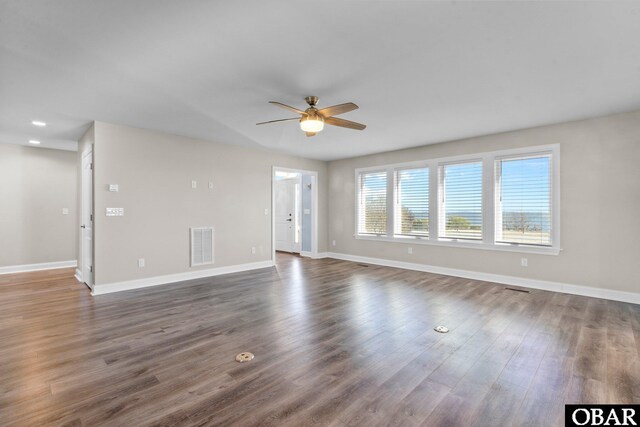 unfurnished living room featuring dark wood-style floors, ceiling fan, visible vents, and baseboards