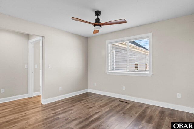 spare room featuring a ceiling fan, visible vents, baseboards, and wood finished floors