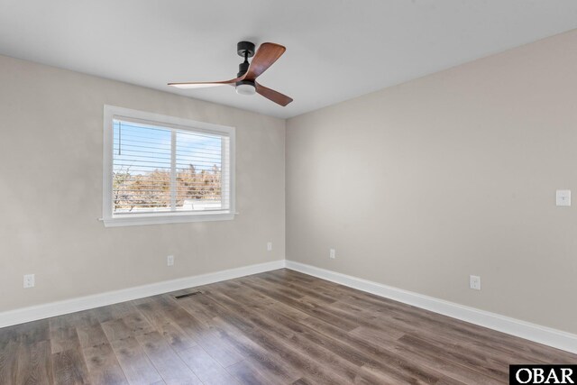 spare room with ceiling fan, visible vents, baseboards, and wood finished floors