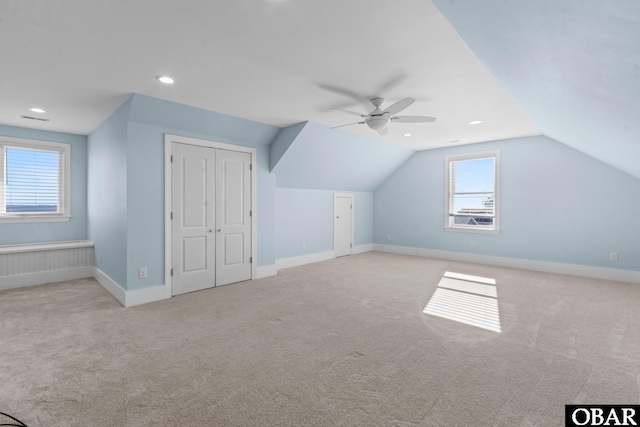 additional living space featuring vaulted ceiling, plenty of natural light, baseboards, and light colored carpet