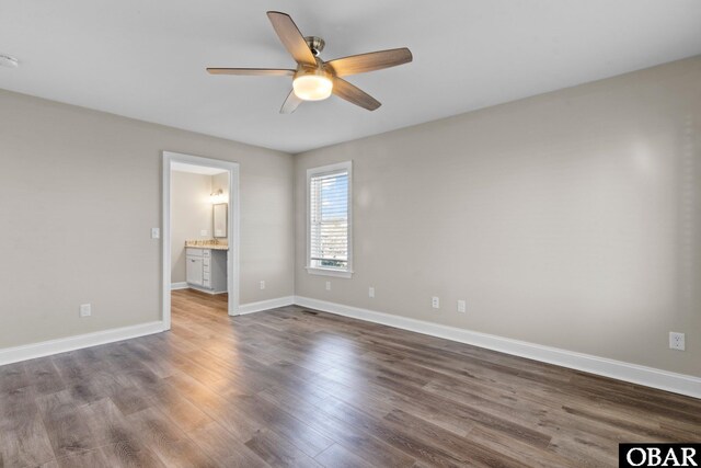 unfurnished bedroom with ceiling fan, ensuite bathroom, wood finished floors, and baseboards