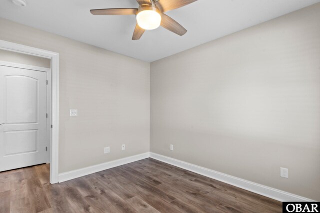 unfurnished room with baseboards, dark wood finished floors, and a ceiling fan