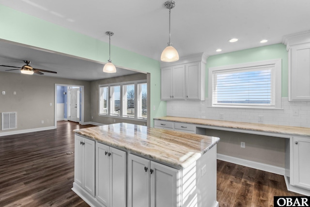 kitchen featuring visible vents, white cabinets, open floor plan, a center island, and hanging light fixtures