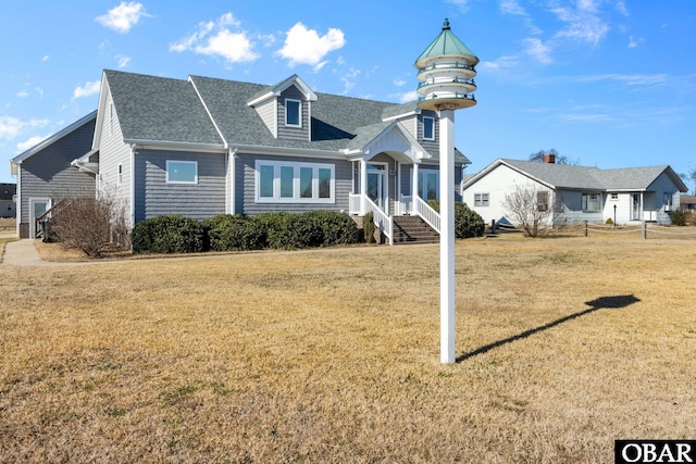 view of front of house featuring a shingled roof and a front yard