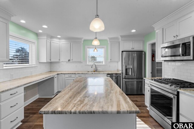 kitchen featuring appliances with stainless steel finishes, white cabinetry, a kitchen island, and hanging light fixtures