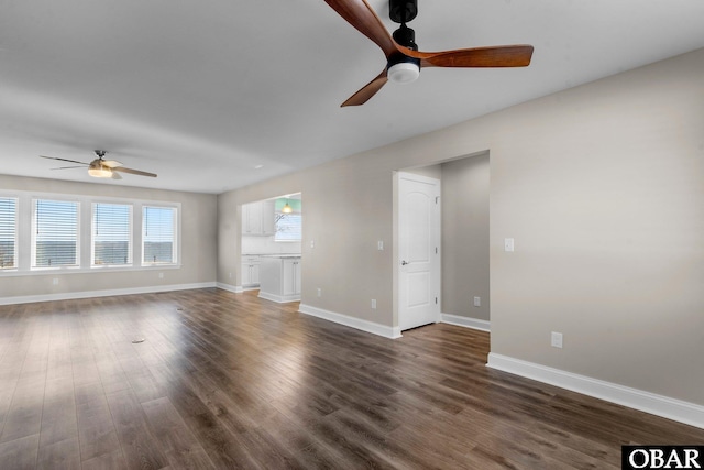 unfurnished living room featuring baseboards, dark wood finished floors, and a ceiling fan