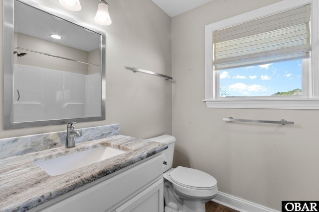 full bath featuring toilet, a shower, vanity, and baseboards