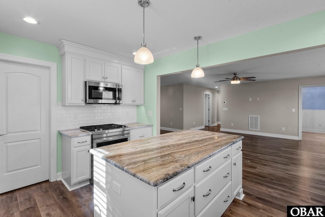 kitchen featuring decorative light fixtures, stainless steel appliances, visible vents, white cabinets, and light stone countertops