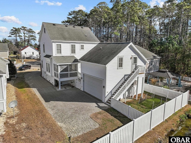 exterior space with roof with shingles, a fenced backyard, driveway, and stairway