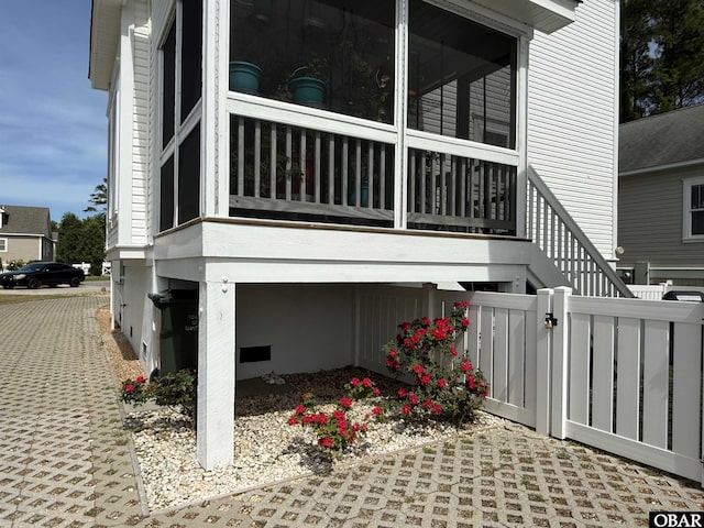 view of side of home with fence, a gate, and a sunroom